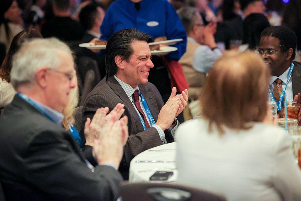 Business people sitting at a roundtable, applauding.