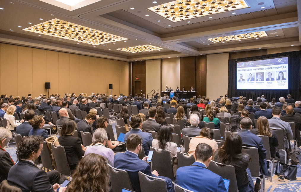 A large audience sitting before a panel of speakers.