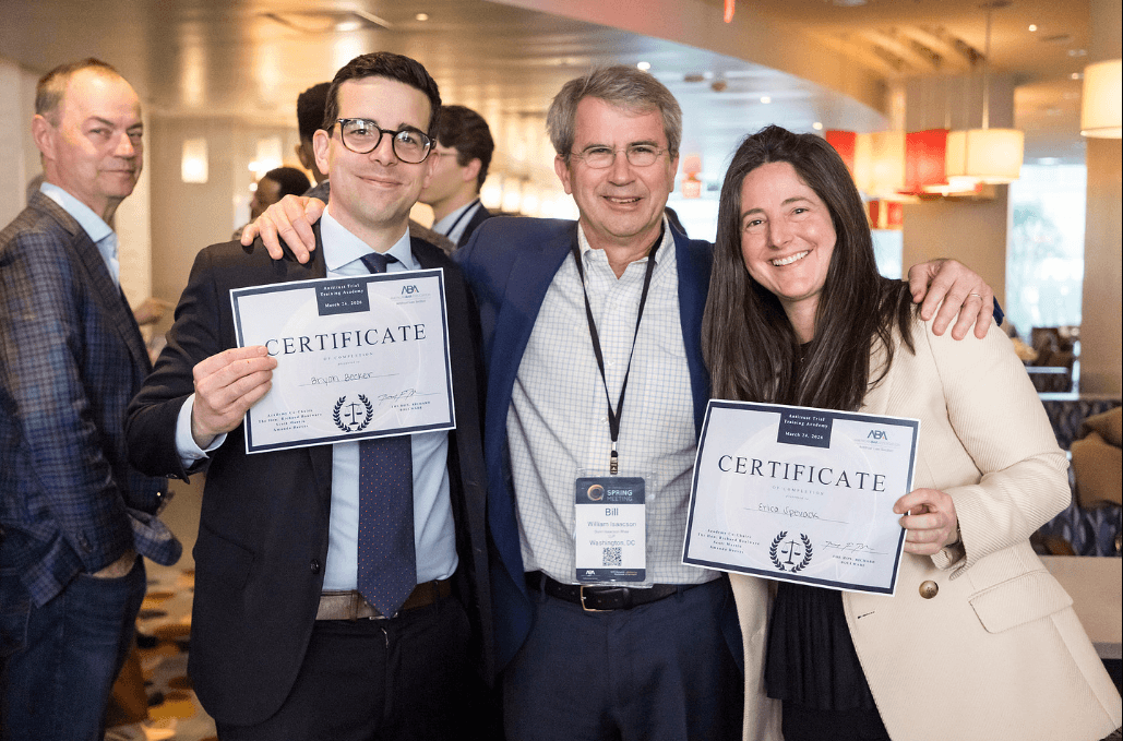 A trio stands arm-in-arm, holding certificates in front of themselves.
